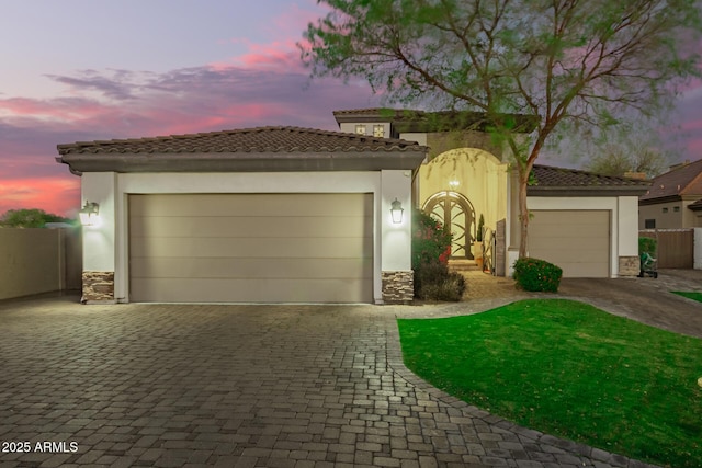 mediterranean / spanish-style home featuring stucco siding, stone siding, and decorative driveway