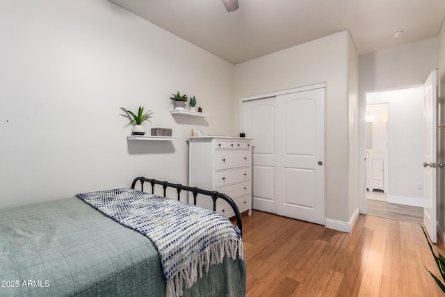 bedroom with a ceiling fan, light wood-style flooring, baseboards, and a closet