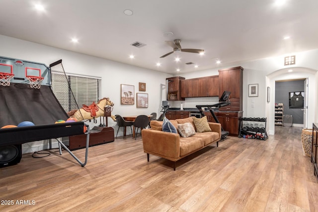 living area featuring visible vents, ceiling fan, light wood-style flooring, recessed lighting, and arched walkways