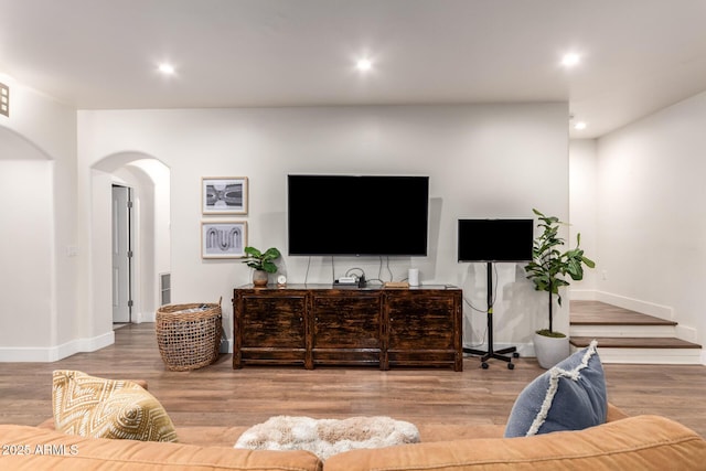 living area featuring recessed lighting, baseboards, arched walkways, and wood finished floors