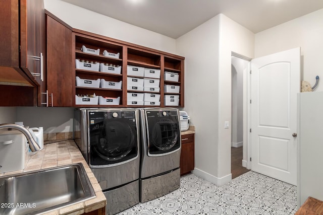 laundry room with washer and clothes dryer, cabinet space, baseboards, and a sink