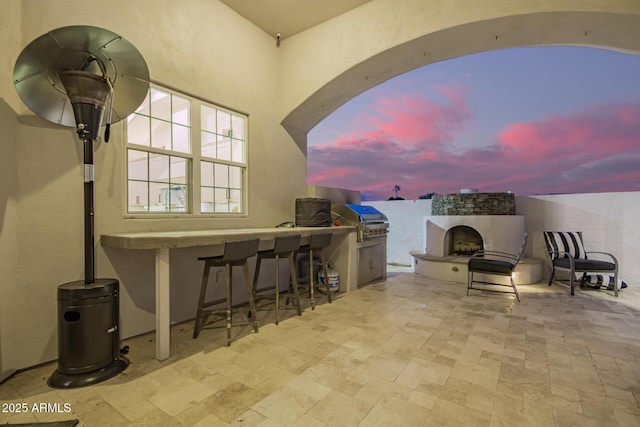 view of patio / terrace featuring area for grilling, outdoor wet bar, a grill, and an outdoor fireplace