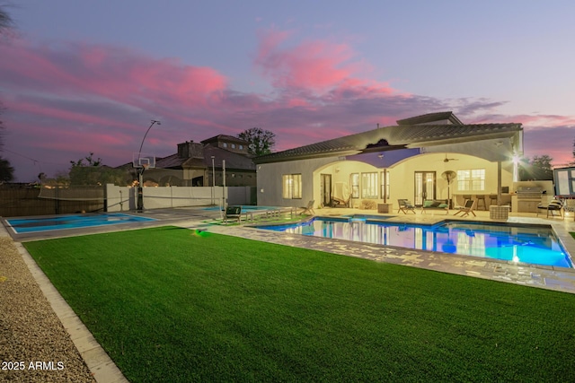 view of swimming pool with a fenced in pool, exterior kitchen, a yard, a fenced backyard, and a jacuzzi