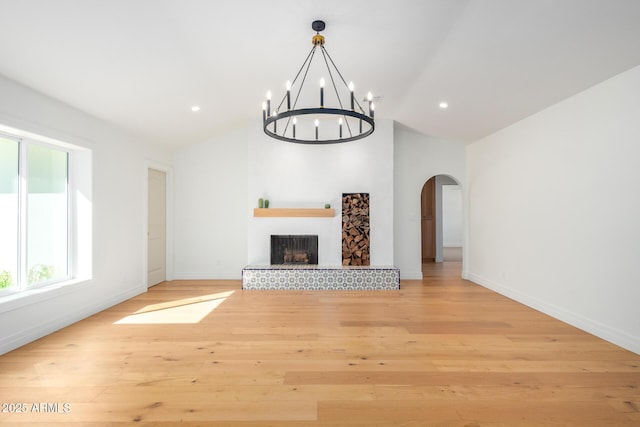 16227 N 63rd Pl, Scottsdale, AZ 85254 - unfurnished living room featuring arched walkways, lofted ceiling, a chandelier, light wood-style flooring, and baseboards