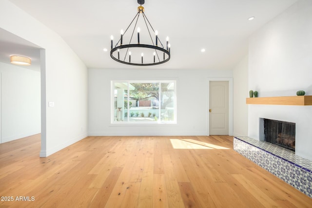 16227 N 63rd Pl, Scottsdale, AZ 85254 - unfurnished living room with a chandelier, light wood-style flooring, a fireplace with raised hearth, baseboards, and recessed lighting