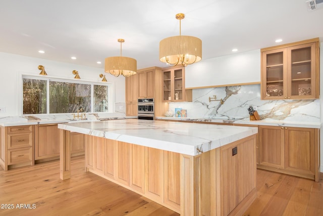 16227 N 63rd Pl, Scottsdale, AZ 85254 - kitchen featuring white gas cooktop, a spacious island, light wood-style flooring, backsplash, and stainless steel double oven