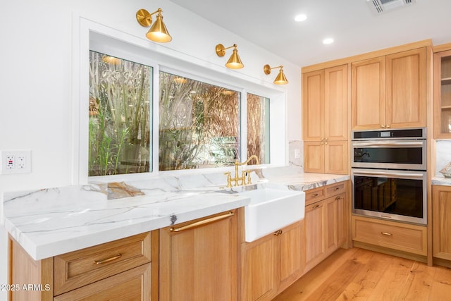 16227 N 63rd Pl, Scottsdale, AZ 85254 - kitchen with a sink, stainless steel double oven, light wood-style floors, light stone counters, and recessed lighting