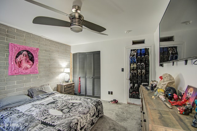 carpeted bedroom with a closet, ceiling fan, and brick wall