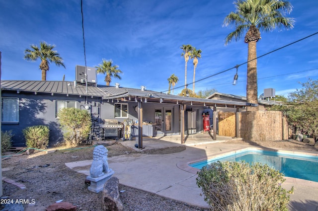 back of property with central AC, a patio area, a fenced in pool, and french doors