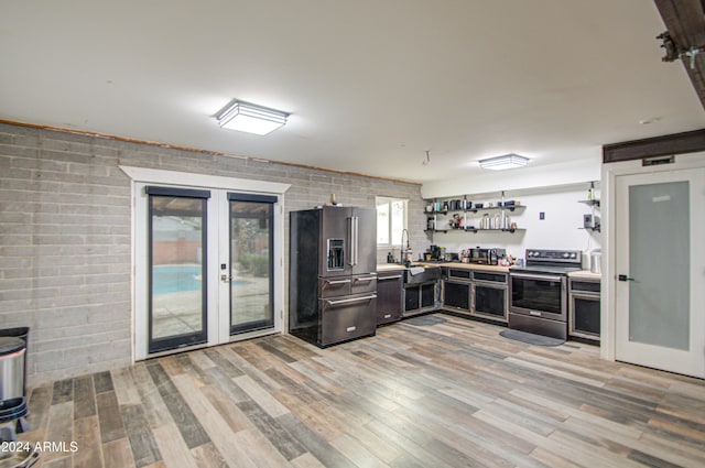 kitchen featuring french doors, stainless steel appliances, light hardwood / wood-style floors, and brick wall