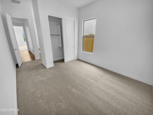 unfurnished bedroom featuring a closet, multiple windows, carpet flooring, and baseboards