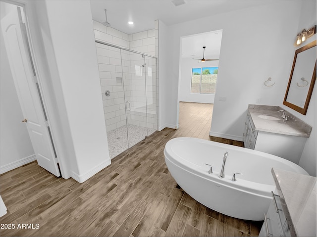 full bath with baseboards, wood finish floors, vanity, and a stall shower