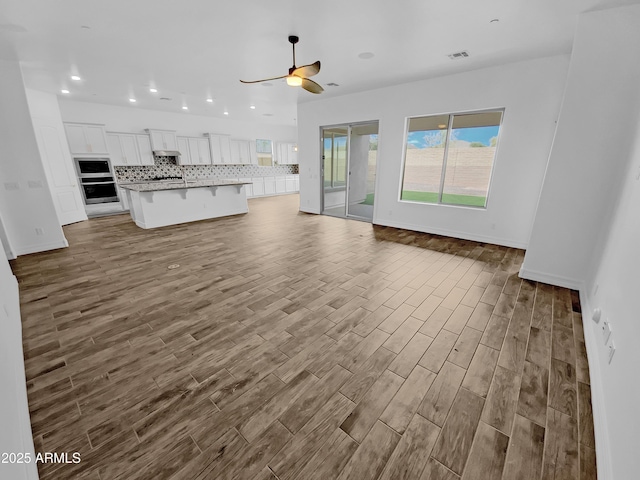 unfurnished living room featuring recessed lighting, wood finished floors, visible vents, baseboards, and a ceiling fan