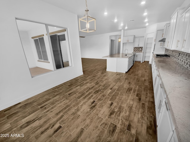 kitchen featuring an island with sink, dark wood-style floors, white cabinetry, and backsplash