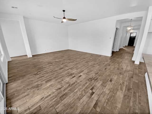 unfurnished living room with visible vents, wood finished floors, and ceiling fan with notable chandelier
