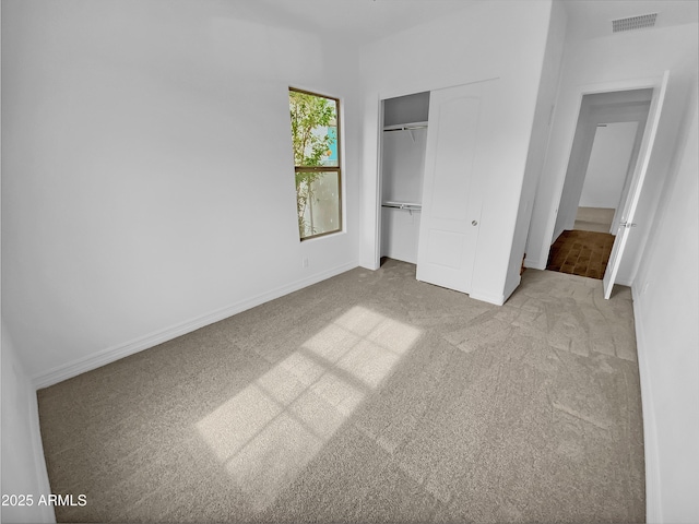 unfurnished bedroom with baseboards, a closet, visible vents, and light colored carpet