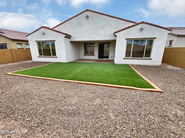 back of property with a tile roof, a yard, stucco siding, a patio area, and fence