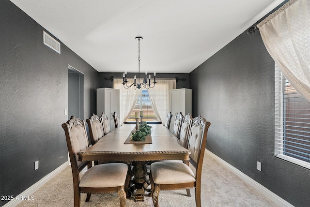 carpeted dining area featuring an inviting chandelier