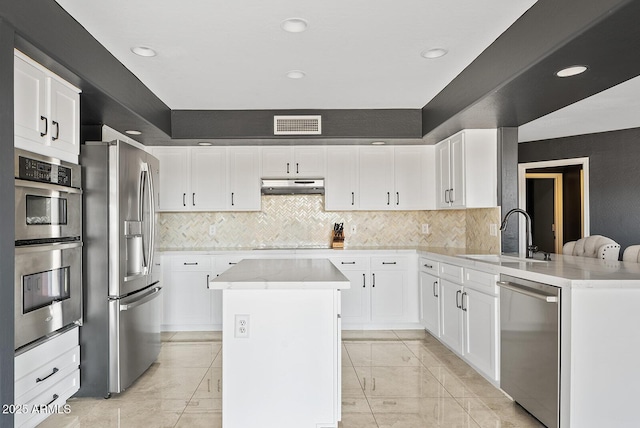 kitchen featuring sink, appliances with stainless steel finishes, backsplash, white cabinets, and kitchen peninsula