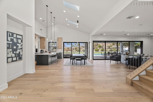 interior space with light wood-type flooring, a skylight, and a towering ceiling