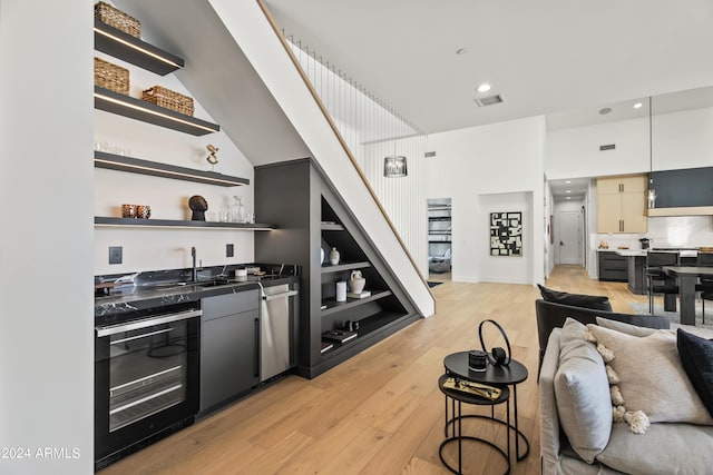 kitchen featuring built in shelves, oven, stainless steel dishwasher, light hardwood / wood-style flooring, and sink