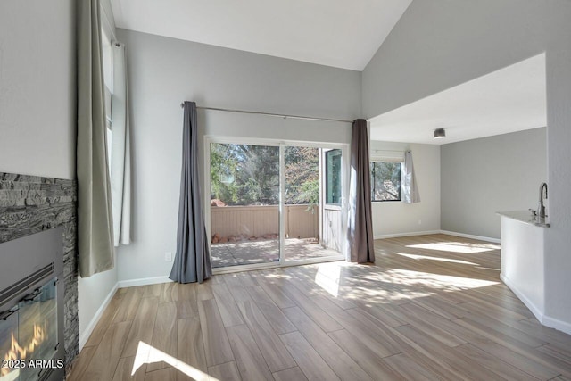 1380 Vista Montana Rd Unit 22, Sedona, AZ 86336 - unfurnished living room featuring a fireplace, light wood-type flooring, high vaulted ceiling, and baseboards