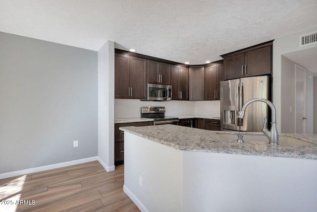 1380 Vista Montana Rd Unit 22, Sedona, AZ 86336 - kitchen with appliances with stainless steel finishes, dark brown cabinetry, baseboards, light stone counters, and backsplash