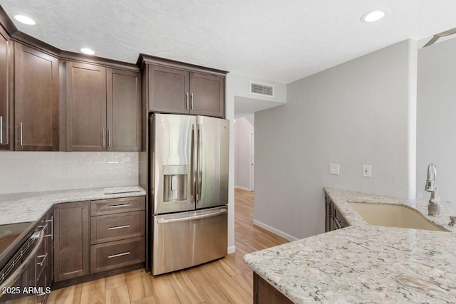 1380 Vista Montana Rd Unit 22, Sedona, AZ 86336 - kitchen with appliances with stainless steel finishes, a sink, light wood-type flooring, light stone countertops, and decorative backsplash