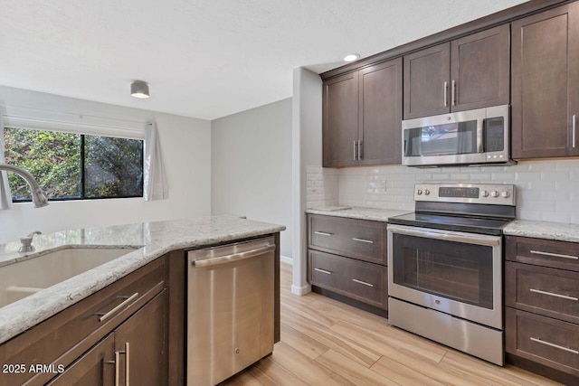 1380 Vista Montana Rd Unit 22, Sedona, AZ 86336 - kitchen featuring appliances with stainless steel finishes, light wood-style floors, a sink, dark brown cabinets, and tasteful backsplash