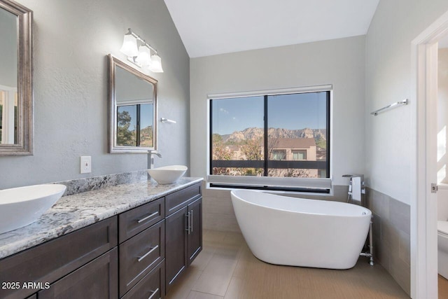 1380 Vista Montana Rd Unit 22, Sedona, AZ 86336 - full bath with double vanity, a freestanding bath, vaulted ceiling, tile walls, and tile patterned floors