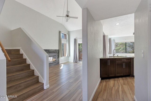 1380 Vista Montana Rd Unit 22, Sedona, AZ 86336 - bar with light wood finished floors, stairway, a ceiling fan, a glass covered fireplace, and a sink