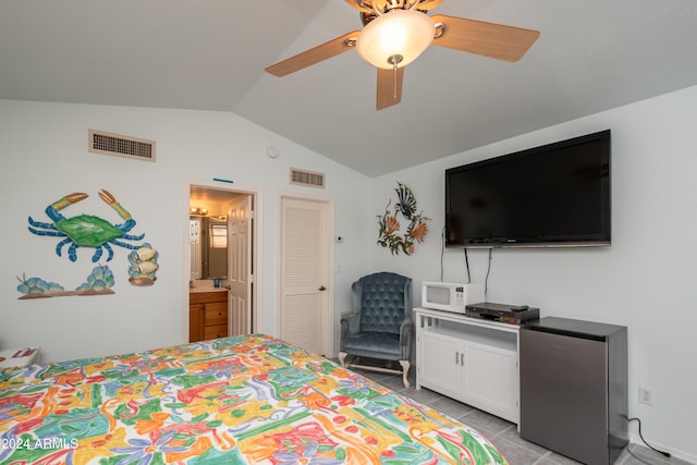 bedroom with connected bathroom, lofted ceiling, stainless steel fridge, light tile patterned floors, and ceiling fan