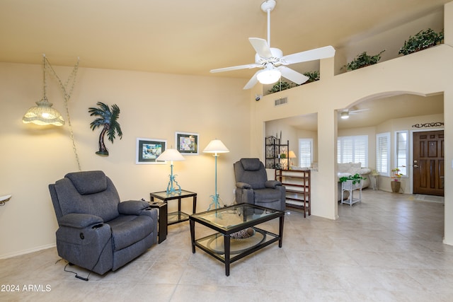 sitting room featuring a towering ceiling, light tile patterned floors, and ceiling fan