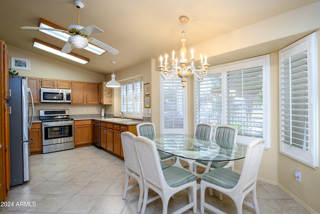 kitchen with lofted ceiling, hanging light fixtures, stainless steel appliances, light tile patterned floors, and ceiling fan with notable chandelier