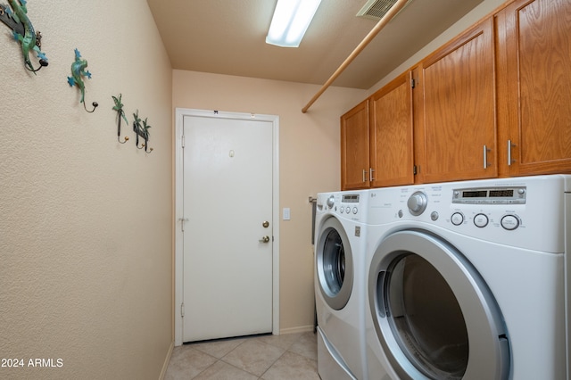 washroom with cabinets, washing machine and clothes dryer, and light tile patterned floors