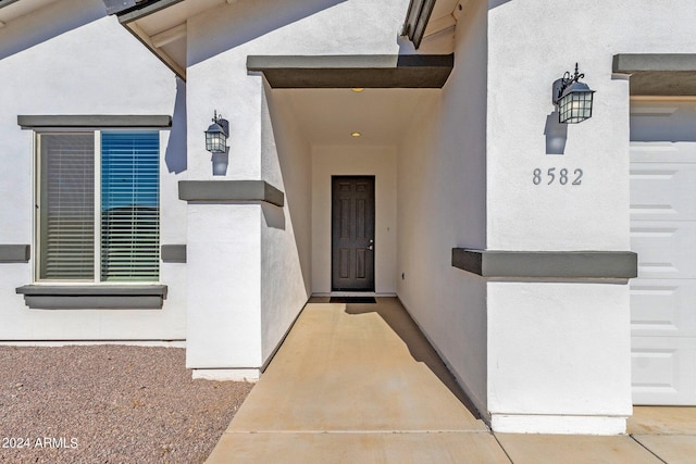 property entrance featuring a garage and stucco siding