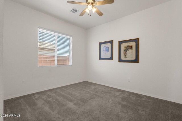 spare room featuring ceiling fan and dark colored carpet