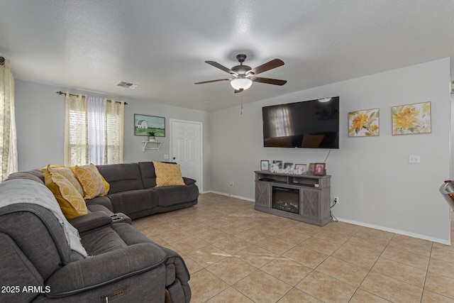 living room with ceiling fan, light tile patterned floors, and a textured ceiling