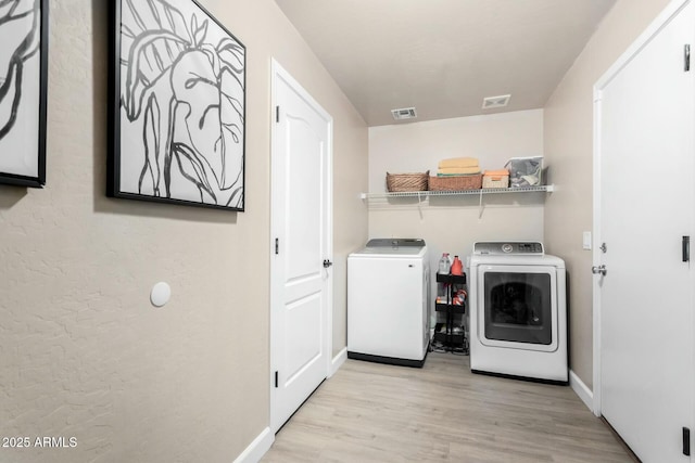 washroom with light hardwood / wood-style flooring and washing machine and dryer