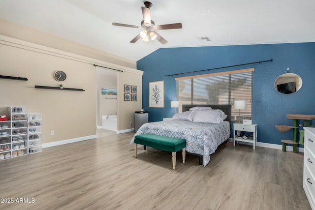 bedroom with lofted ceiling, light hardwood / wood-style flooring, a barn door, and ceiling fan