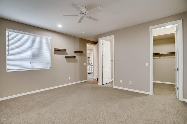 unfurnished bedroom featuring ceiling fan, light colored carpet, a walk in closet, and a closet