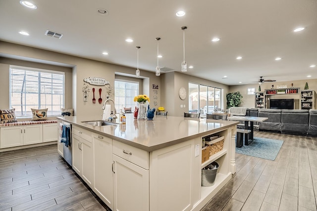 kitchen with white cabinetry, sink, ceiling fan, an island with sink, and decorative light fixtures