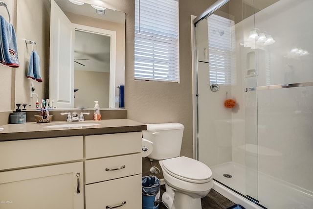 bathroom with vanity, ceiling fan, toilet, and walk in shower