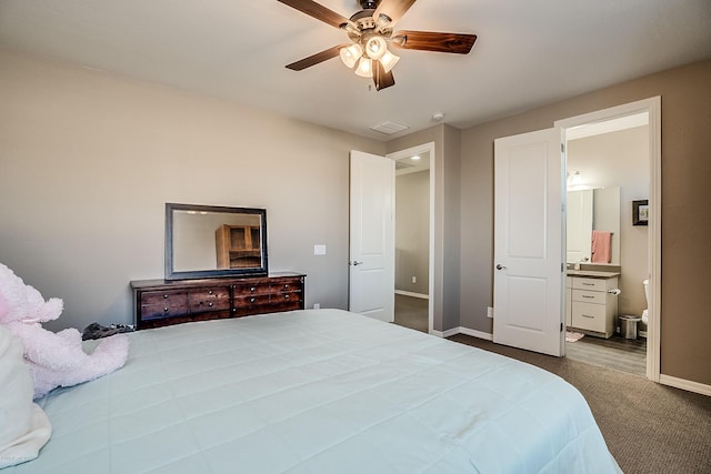 bedroom with ensuite bathroom, dark carpet, and ceiling fan