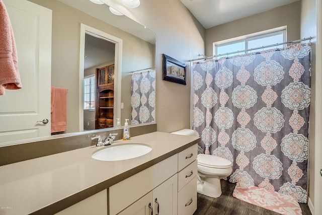 bathroom featuring a wealth of natural light, toilet, vanity, and hardwood / wood-style flooring