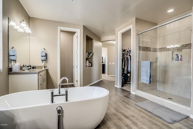 bathroom featuring plus walk in shower, wood-type flooring, and vanity