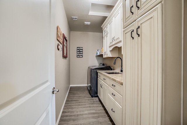 kitchen with sink, light stone countertops, independent washer and dryer, a textured ceiling, and wood-type flooring