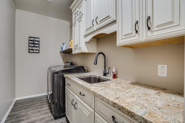 laundry area with cabinets, washing machine and dryer, sink, and hardwood / wood-style flooring