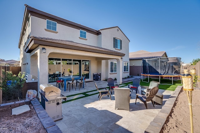 rear view of house featuring a patio area and a trampoline