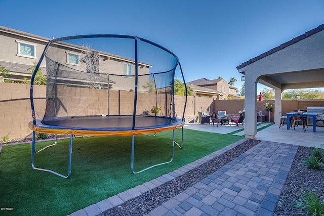 view of yard featuring a trampoline and a patio